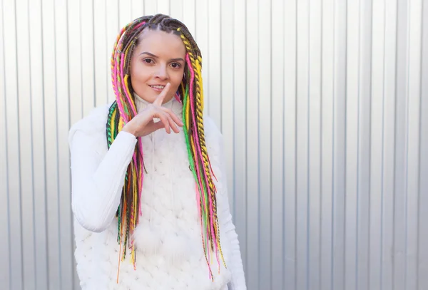 Beautiful girl with colored dreadlocks summer sunny day in a white jacket and lips finger asking for silence — Stock Photo, Image