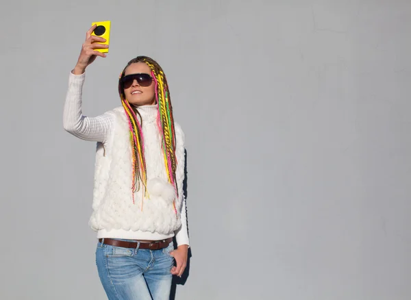 Beautiful girl with colored dreadlocks summer sunny day in a white jacket makes selfie — Stock Photo, Image