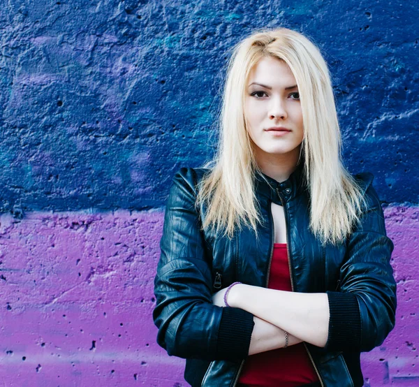 Portrait of a beautiful blonde girl near the purple pink wall with arms folded — Stock Photo, Image