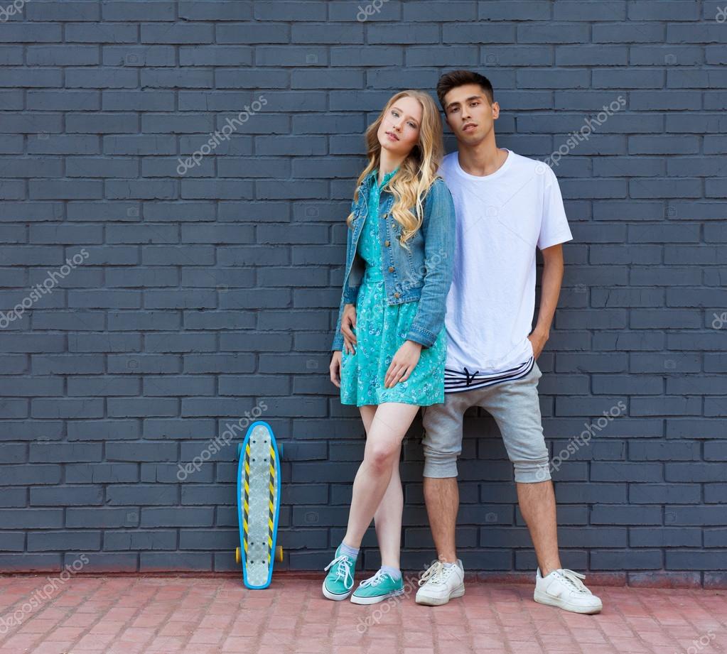 Interracial young couple in love outdoor whis skateboard. Stunning sensual outdoor portrait of young stylish fashion couple posing in summer pic