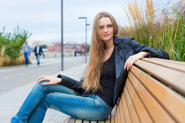 一个漂亮的女孩在公园里坐在板凳上的肖像。关闭 — 图库照片