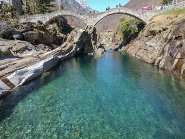 Lavertezzo, İsviçre - 24 Mart 2021: İsviçre 'nin italyan kesimindeki Verzasca vadisinde Lavertezzo' nun ünlü Roma köprüsünü ziyaret eden turistler
