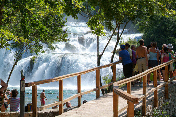 Tourists walking in front of the waterfalls of the Krka 