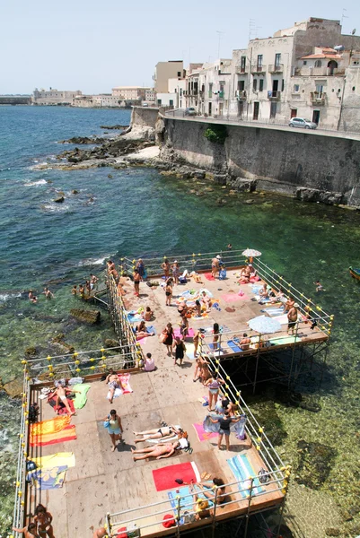 La gente prende il sole sulla costa di Siracusa in Sicilia — Foto Stock