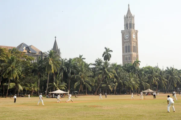 Gente jugando al cricket frente a la Torre Rajabai en Mumbai —  Fotos de Stock