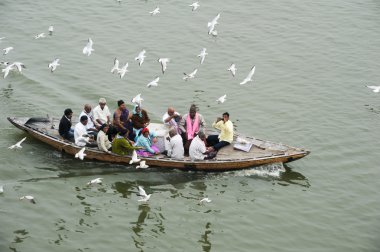 Tourists taking a boat tour on the sacred Ganges river clipart