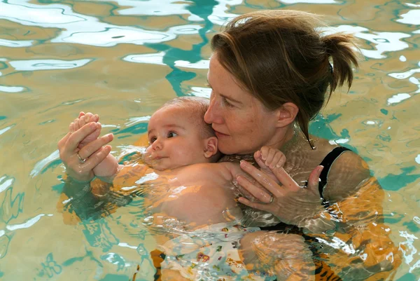 Schattige baby genieten van zwemmen in een zwembad met zijn moeder — Stockfoto