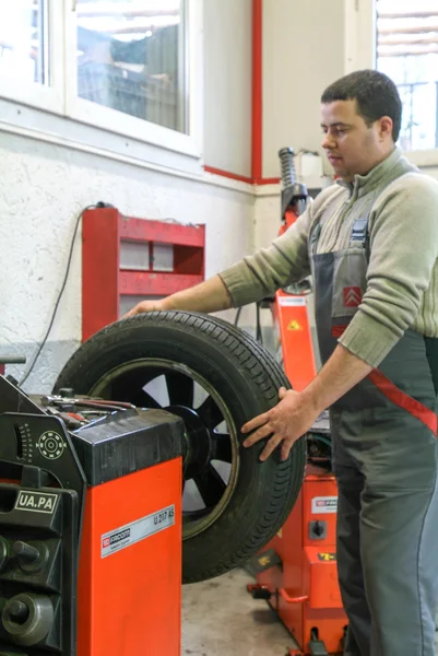 Auto mecánico cambia un neumático en su garaje — Foto de Stock