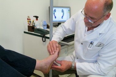 Doctor preparing orthopedic insoles for a patient on his studio clipart