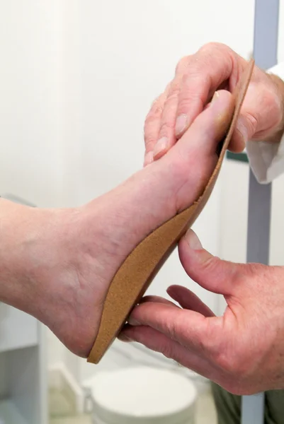 Médecin préparant des semelles orthopédiques pour un patient Image En Vente