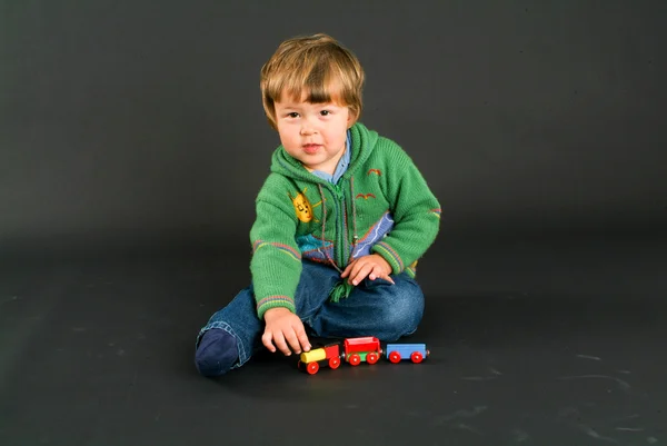 Kleiner Junge posiert mit einer bunten Spielzeugeisenbahn — Stockfoto