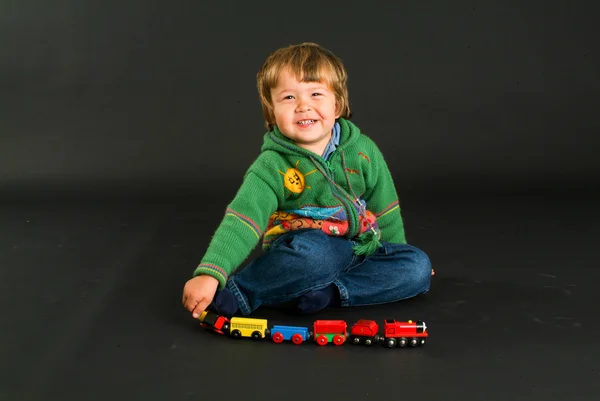 Kleiner Junge posiert mit einer bunten Spielzeugeisenbahn — Stockfoto