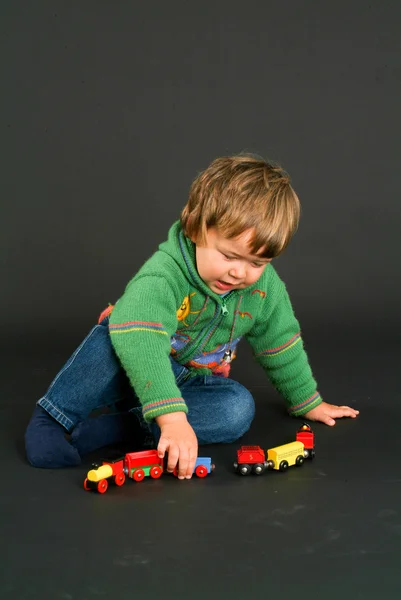 Kleiner Junge posiert mit einer bunten Spielzeugeisenbahn — Stockfoto