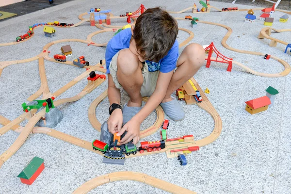 Menino brincando com um conjunto de trem de madeira — Fotografia de Stock