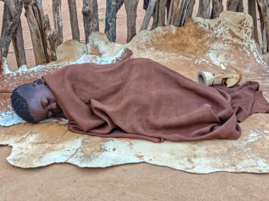 Turmi, Etiyopya - 14 Ağustos 2025: Etiyopya yakınlarındaki Hamer kabilesi köyünde yerde uyuyan çocuk