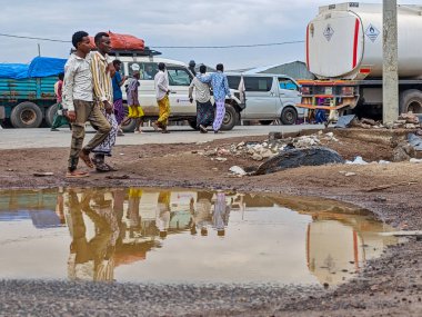 Afdera, Etiyopya - 20 Ağustos 2025: Etiyopya 'da Afdera' nın çamurlu sokaklarında yürüyen insanlar