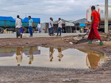 Afdera, Etiyopya - 20 Ağustos 2025: Etiyopya 'da Afdera' nın çamurlu sokaklarında yürüyen insanlar