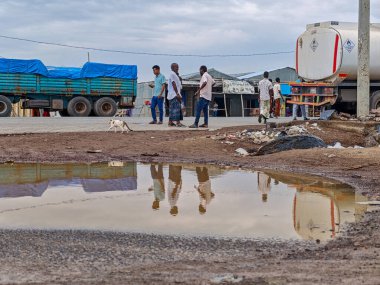 Afdera, Etiyopya - 20 Ağustos 2025: Etiyopya 'da Afdera' nın çamurlu sokaklarında yürüyen insanlar