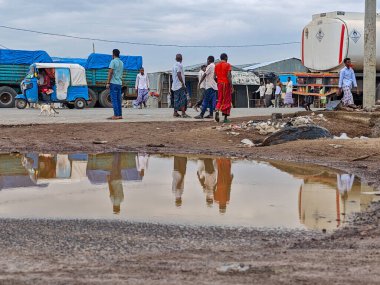 Afdera, Etiyopya - 20 Ağustos 2025: Etiyopya 'da Afdera' nın çamurlu sokaklarında yürüyen insanlar