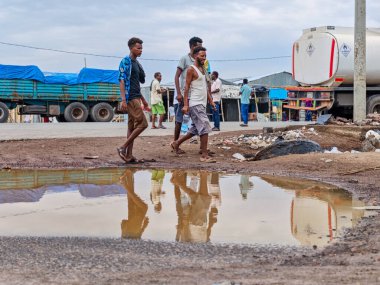 Afdera, Etiyopya - 20 Ağustos 2025: Etiyopya 'da Afdera' nın çamurlu sokaklarında yürüyen insanlar