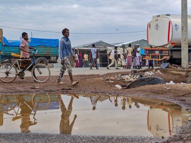 Afdera, Etiyopya - 20 Ağustos 2025: Etiyopya 'da Afdera' nın çamurlu sokaklarında yürüyen insanlar