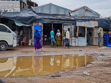 Afdera, Etiyopya - 20 Ağustos 2025: Etiyopya 'da Afdera' nın çamurlu sokaklarında yürüyen insanlar