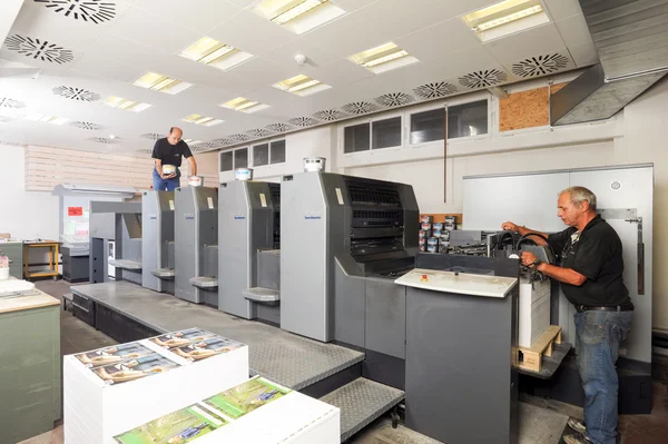 Pessoas que trabalham em uma máquina de impressão offset — Fotografia de Stock