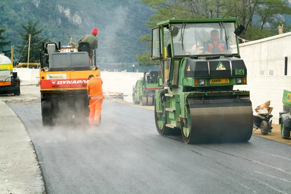 Trabalhadores e veículos durante a asfaltação da estrada — Fotografia de Stock