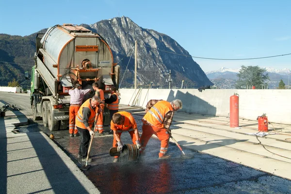 Trabajadores y vehículos durante el asfalto de la carretera — Foto de Stock