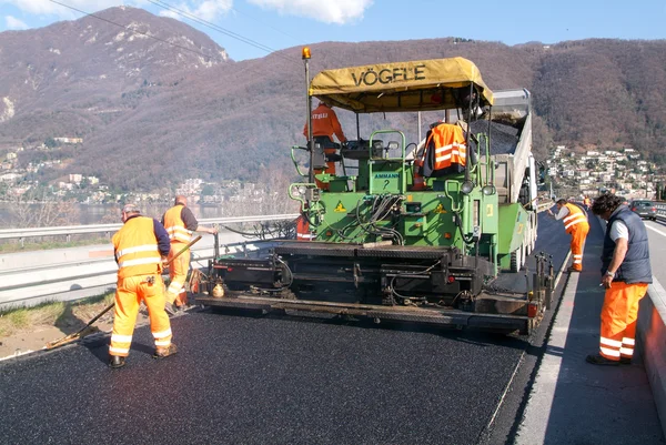 Werknemers en voertuigen tijdens de asfaltering van de snelweg — Stockfoto