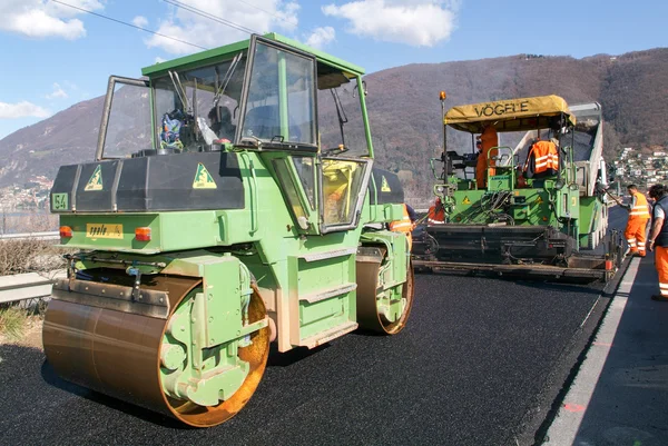 Trabajadores y vehículos durante el asfalto de la carretera — Foto de Stock