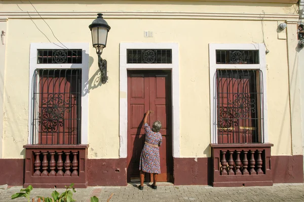 Mujer abriendo la puerta de entrada de su casa colonial —  Fotos de Stock