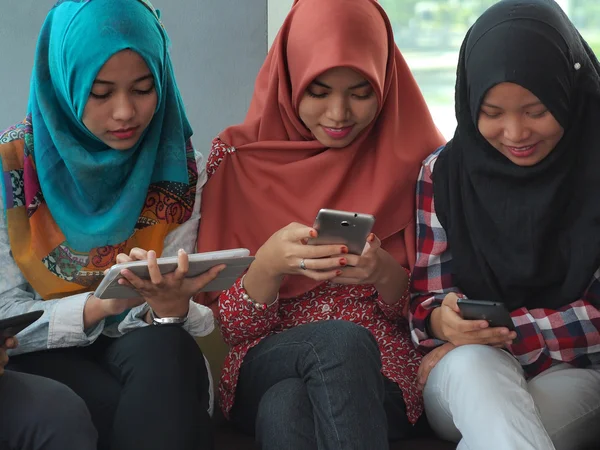 Three muslim girls using mobile device — Stock Photo, Image
