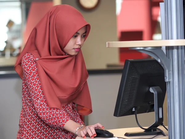 A muslim student using a computer terminal Royalty Free Stock Photos