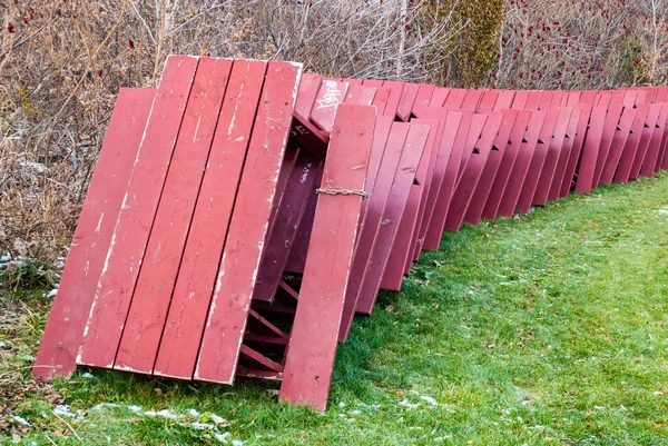 Tavoli da picnic rossi impilati per lo stoccaggio invernale nel parco . — Foto Stock