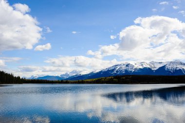 Jasper, Alberta, Kanada 'da bulutların ve gökyüzünün altındaki küçük göl.