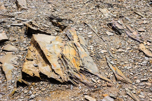 Close-up of layered rocks and gravel on ground.