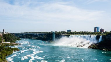 NIAGARA FALLS, CANADA - 27 Ağustos 2017: Niagara Nehri 'ndeki Gökkuşağı Köprüsü' nün altından geçen tekneler şelaleleri ziyaret ediyor.