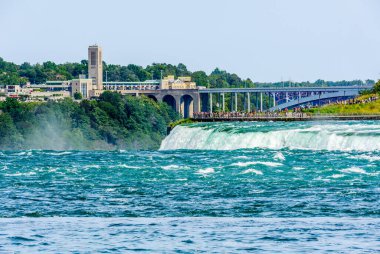 NIAGARA FALLS, CANADA - 27 Ağustos 2017: Turistler arka planda köprüler ve sınır kapısının Kanada tarafında yer alan Amerikan tarafındaki bir platformdan Horseshoe Falls 'u görüyorlar..