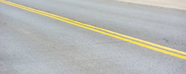Gri asfalt yolda köşegenli sarı çizgiler..