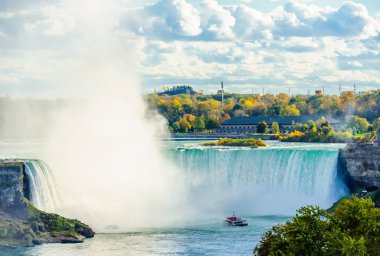 NIAGARA FALLS, CANADA - 26 Ekim 2017: Renkli sonbahar ağaçlarıyla çevrili Horseshoe Şelalesi 'ne bir tur botu yaklaşıyor.