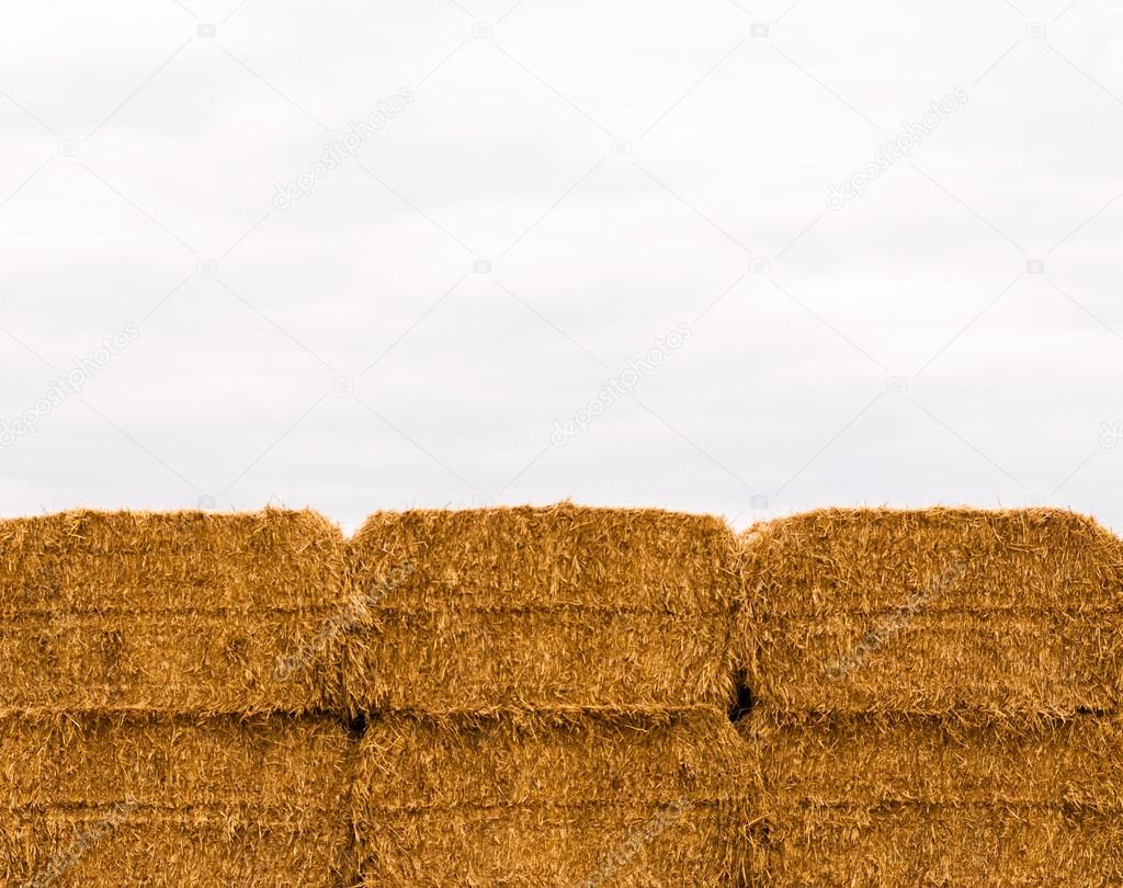 Six stacked yellow hay bales on overcast sky