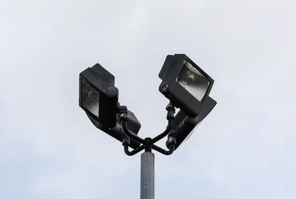 Four black flood lights at top of post — Stock Photo, Image