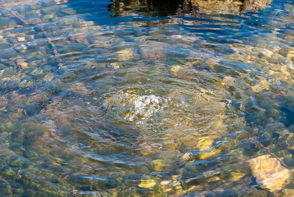 Wody wypływajacej w staw zielony skał. — Zdjęcie stockowe