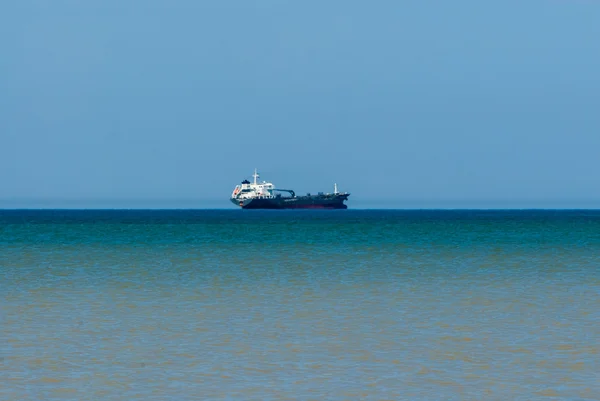 Cargo fartyget i avstånd på vatten blekning i brun grundområden. — Stockfoto