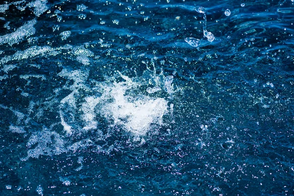 Salpicaduras de agua y gotas en la superficie azul — Foto de Stock