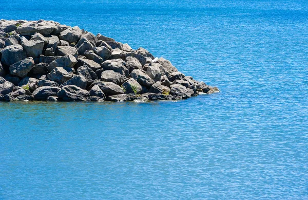 Edge of rocky breakwall ending in water — Stock Photo, Image