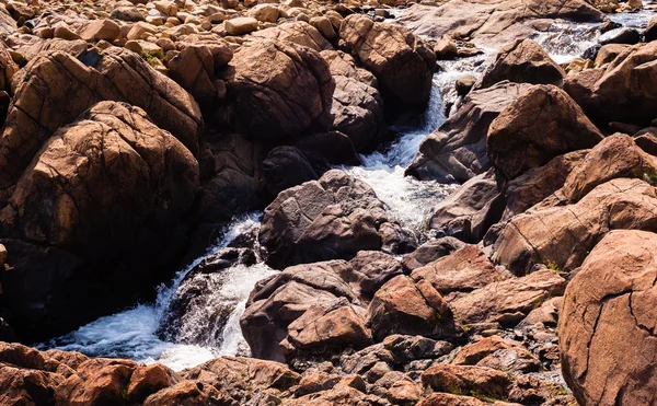 Stream flödar och stänk bland kala röda klippor — Stockfoto