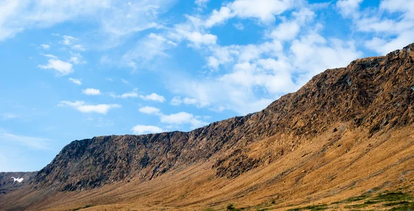 Rocky dry yellow cliff slope against light blue sky — Stock Photo, Image