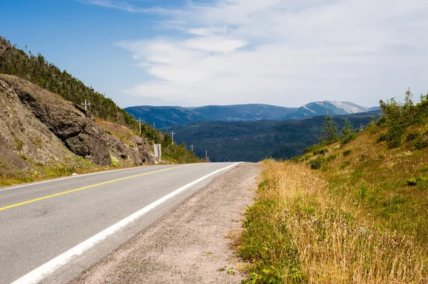 Tom asfalterad väg och grus axeln mot kullar och berg — Stockfoto